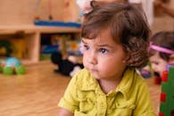 Charming toddler with curly hair in a vibrant playroom, focusing on toys.