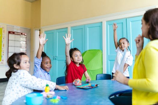 Children eagerly raising hands in a colorful classroom, engaged in learning.