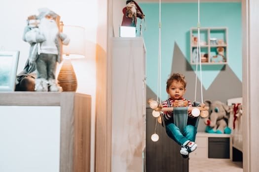 Cute child sitting on a swing with lights in a cozy indoor nursery setting.