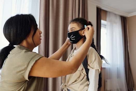 Mother assists daughter with wearing a face mask indoors for safety.