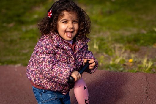 Smiling child enjoying a scooter ride on a sunny day in a park in Istanbul, Türkiye.