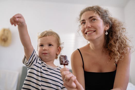 A joyful mother and child enjoying ice cream together in a cozy home setting.