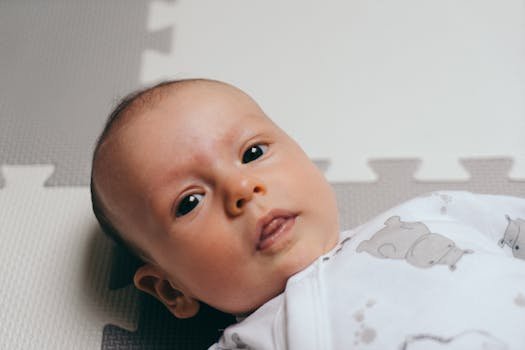 Cute baby lying on a playmat in Poznań, showcasing a serene facial expression.