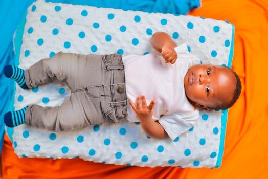 Cute baby lying on a colorful polka dot blanket, looking curious and playful.