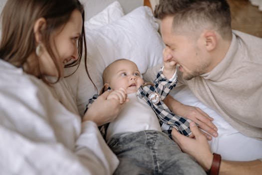 Happy family scene with parents and baby boy playing and smiling indoors.
