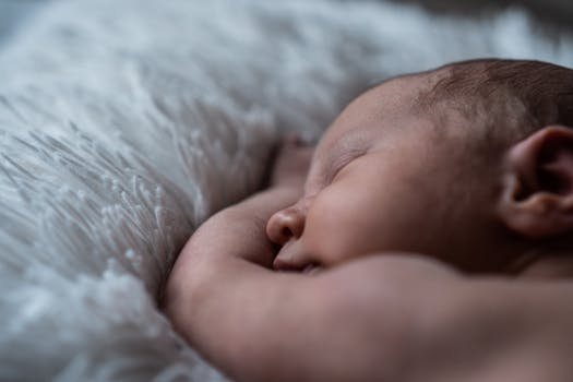 Close-up of a peaceful sleeping newborn baby on a soft white blanket.