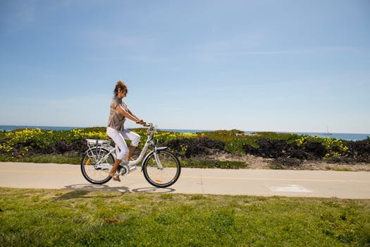 A woman enjoys a ride on an electric bike along a scenic beachside path.
