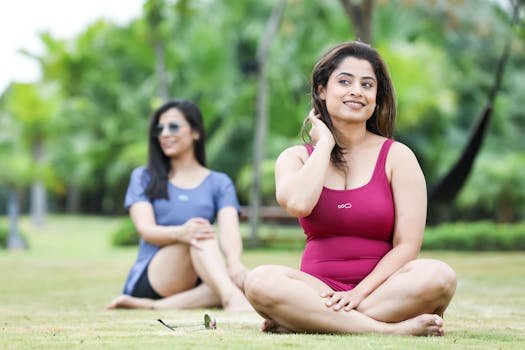 Two women relaxing and doing yoga in a sunny park in Bengaluru, India.
