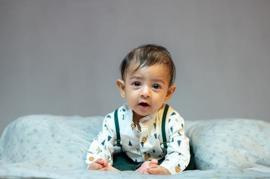 Charming baby boy in a patterned outfit indoors, looking curious and engaged, ideal for lifestyle and parenting themes.