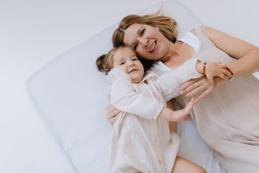 Smiling mother and child lying on a bed enjoying quality bonding time together.
