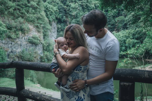 A family enjoys a tender moment outdoors by a cliffside, cuddling their baby in a serene natural setting.