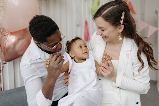 A joyful interracial couple celebrating a birthday with their baby indoors.