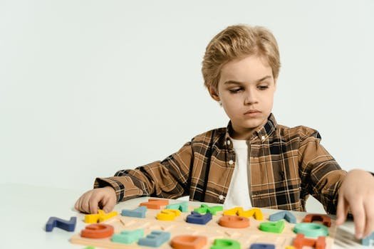 A young boy concentrates on assembling a colorful alphabet puzzle indoors, promoting educational play.
