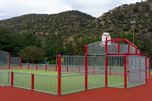 Vibrant outdoor basketball court set against scenic mountain landscape under a cloudy sky.
