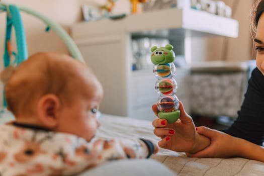 Mother and baby enjoying playful interaction indoors, focusing on a colorful toy.