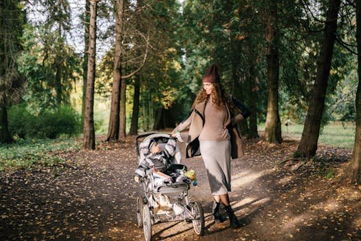A woman with a stroller enjoys a walk in an autumn forest, surrounded by colorful trees.