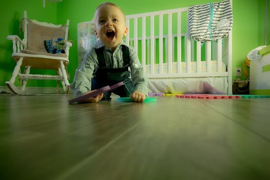 Delightful baby boy crawling on a wooden floor, playing happily in a vibrant green nursery.