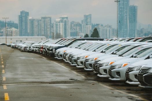 White cars lined up in a parking lot with a city skyline backdrop.