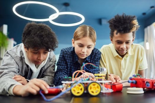 Young students focus on building a robotics project together, showcasing teamwork and creativity.