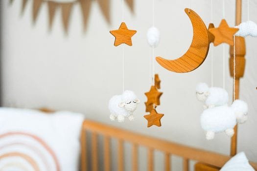 Wooden crib mobile featuring stars, a crescent moon, and fluffy sheep for a cozy baby nursery.