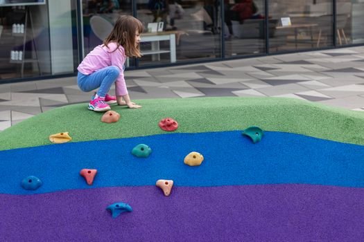 Young girl enjoying climbing a vibrant playground structure in Zagreb.