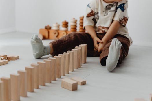 A young child sits indoors playing with wooden blocks, emphasizing creativity and learning.