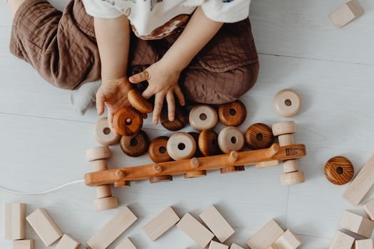 Young child playing with wooden blocks and wheels, fostering creativity.