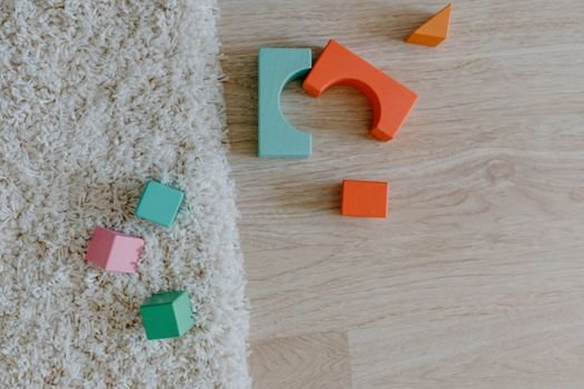 Close-up of colorful wooden blocks on a carpet and wooden floor.