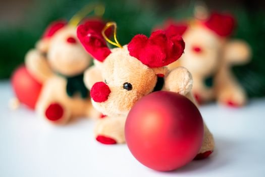 Close-up of a reindeer plush decoration with a red Christmas ornament, creating a festive holiday scene.