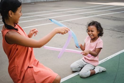 Two children having fun playing with colorful balloons outdoors, laughing and enjoying a playful moment.