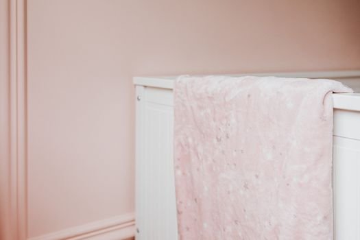 A pastel pink blanket with star patterns draped over a white crib in a nursery.