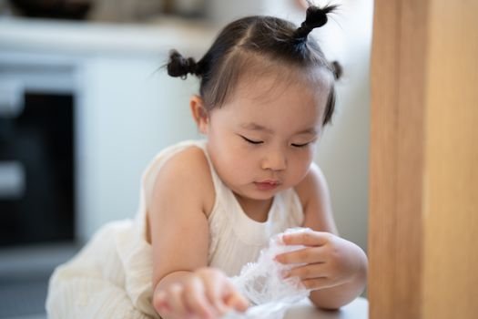 Young child playing indoors with focused expression, showcasing innocence and curiosity.