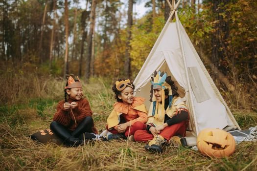 Kids enjoy a fall camping trip in costumes with a carved pumpkin.
