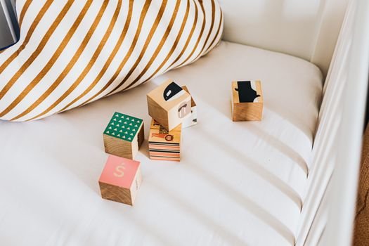 A set of colorful wooden blocks on a white bed with a striped pillow.