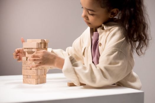 Child playing thoughtfully with wooden blocks displaying emotional words.