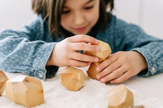 A young girl stacking wooden blocks, engaging in mindful play for cognitive development.